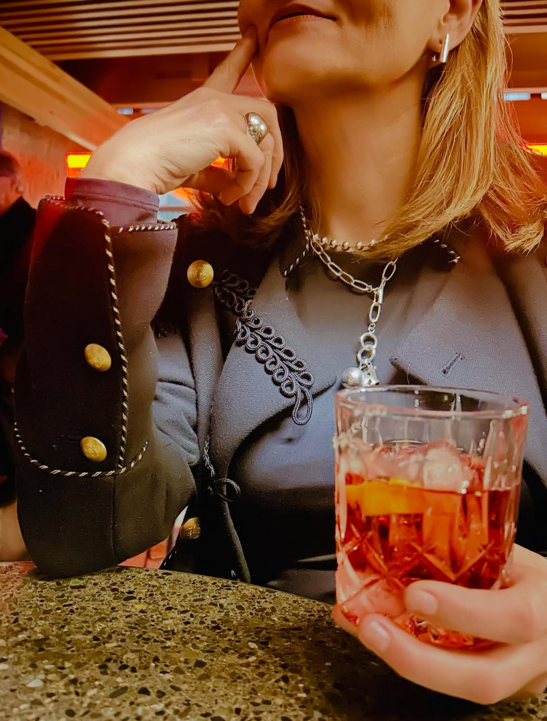 A silver huggie, bead choker, chain and dome ring worn in a warm evening room.